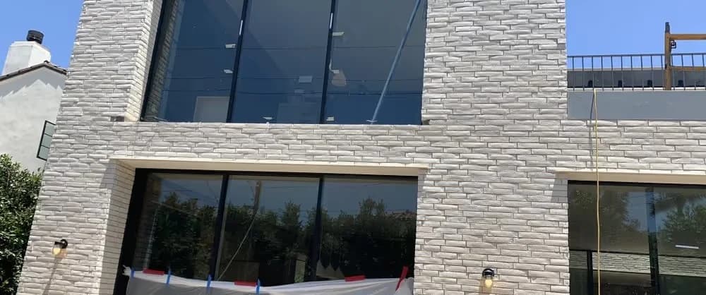 A completed Akopi Builders home with a stone facade and large glazed openings.